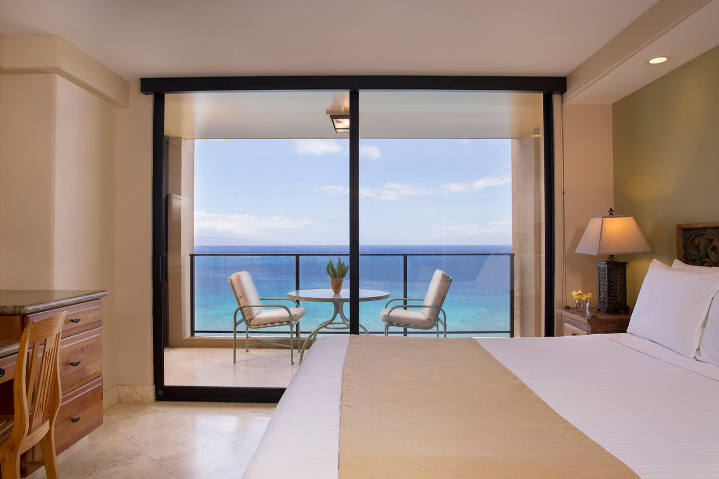 Room with a bed, night stand, lamps, couch, balcony.