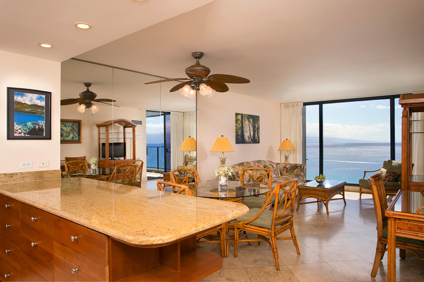 Living room with a couch, coffee table, desk, dining area, and balcony with oceanfront view. 