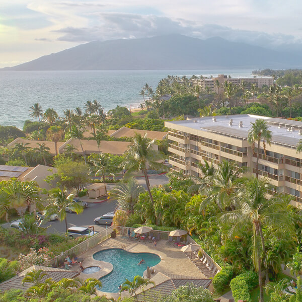 Overhead view of resort with pool, building, tropical lanscape, with ocean and mountain views in background