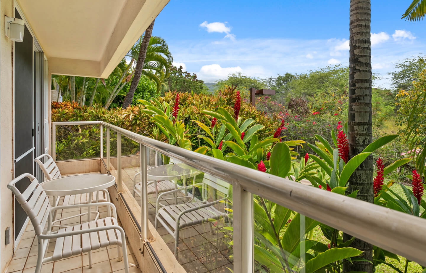 Balcony with chairs, table, view of resort gardens.