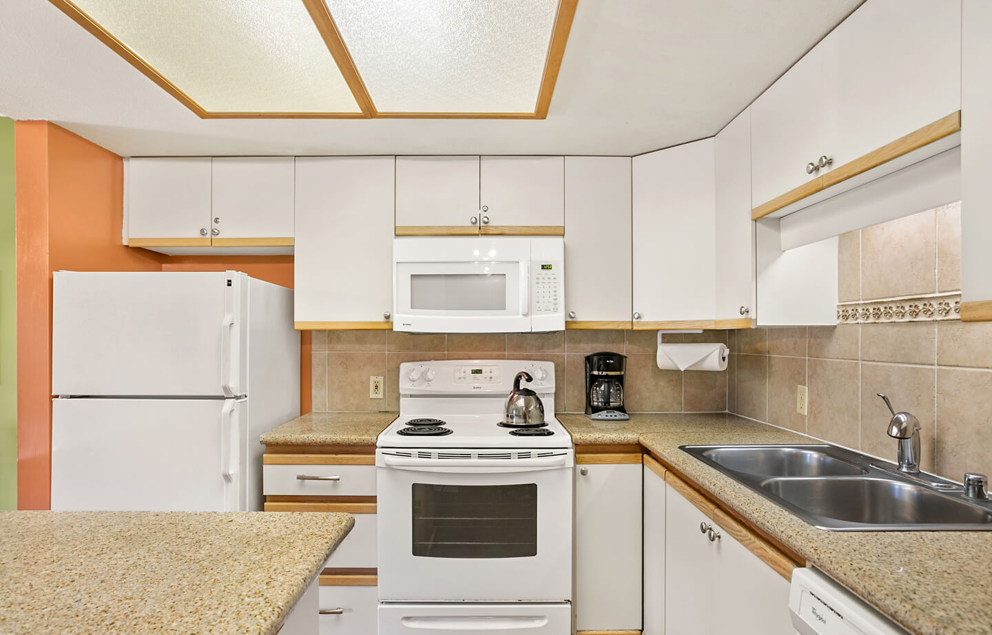 Kitchen with refrigerator, stove, microwave, sink, counters, and cabinets.