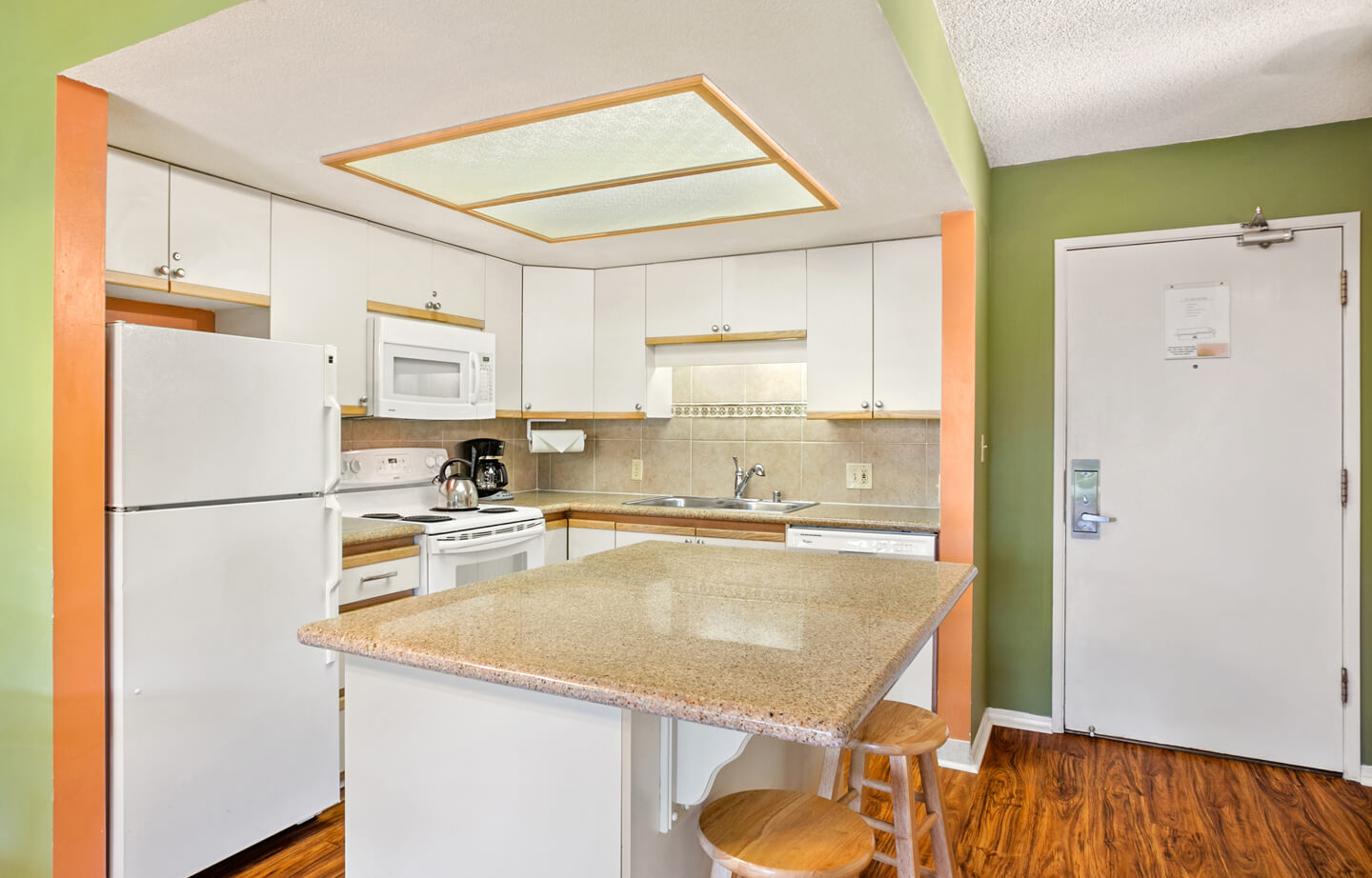 Kitchen with island counter, refrigerator, microwave, stove, sink.