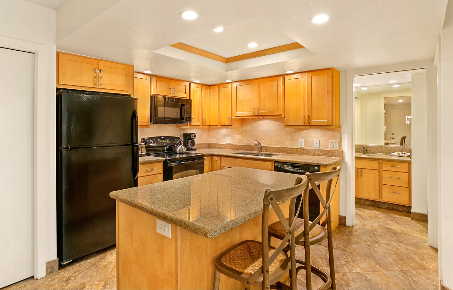 Kitchen with island counter, refrigerator, microwave, stove, sink.