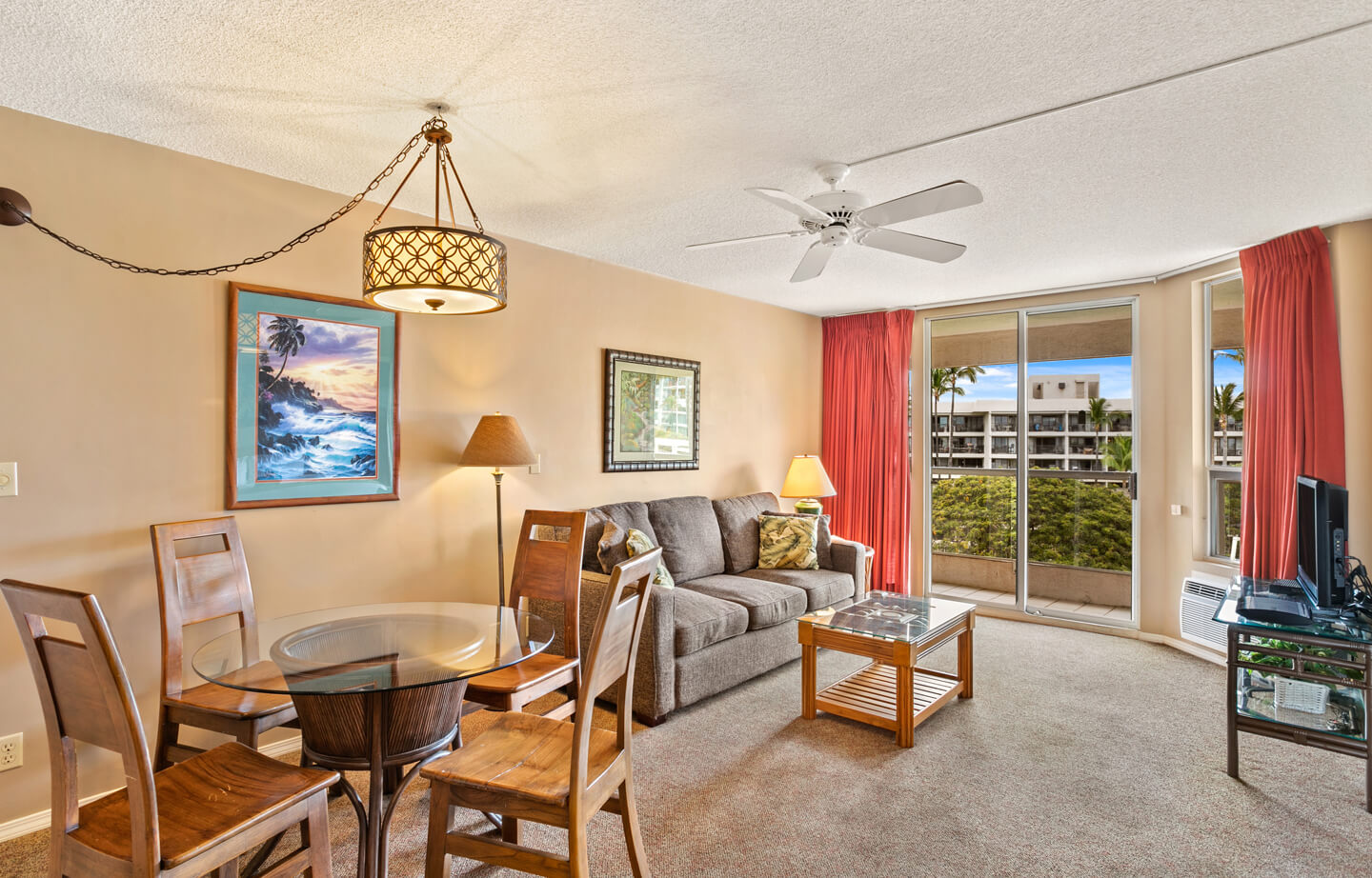 Living area with a couch, coffee table, TV, dining area, and balcony.