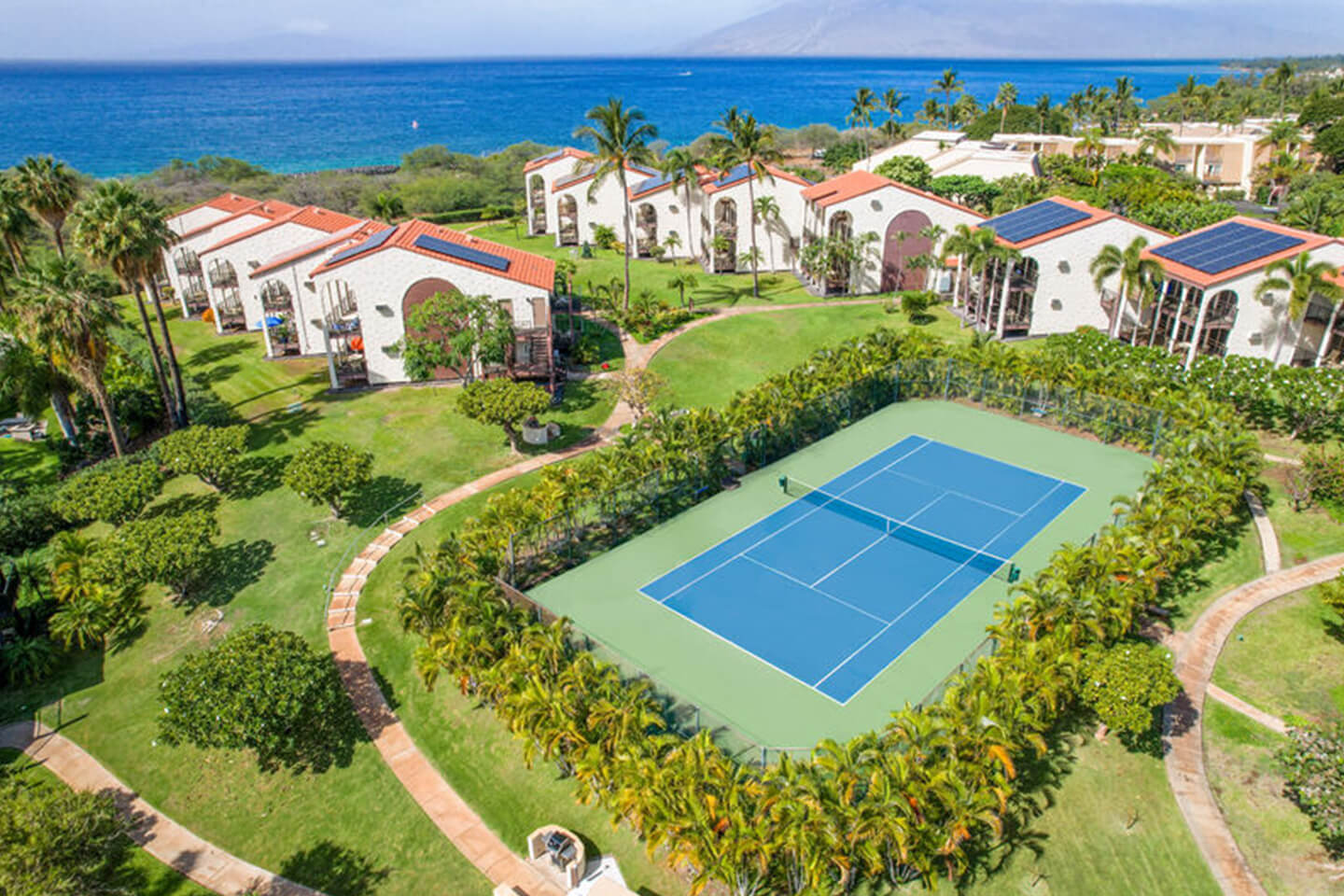 Aerial view of resort, tennis court, and ocean.
