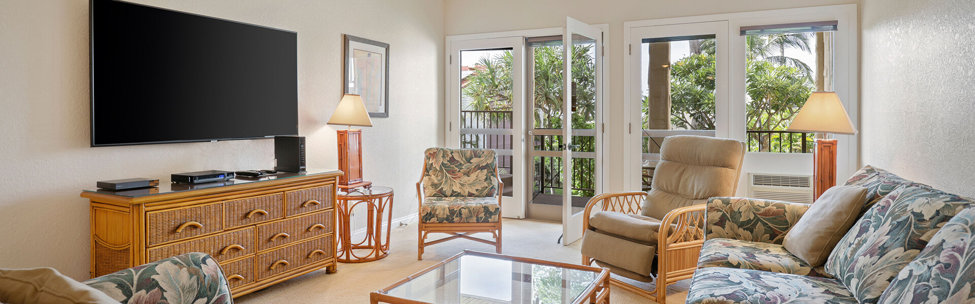 Living area with a couch, coffee table, TV, lamp, and balcony.