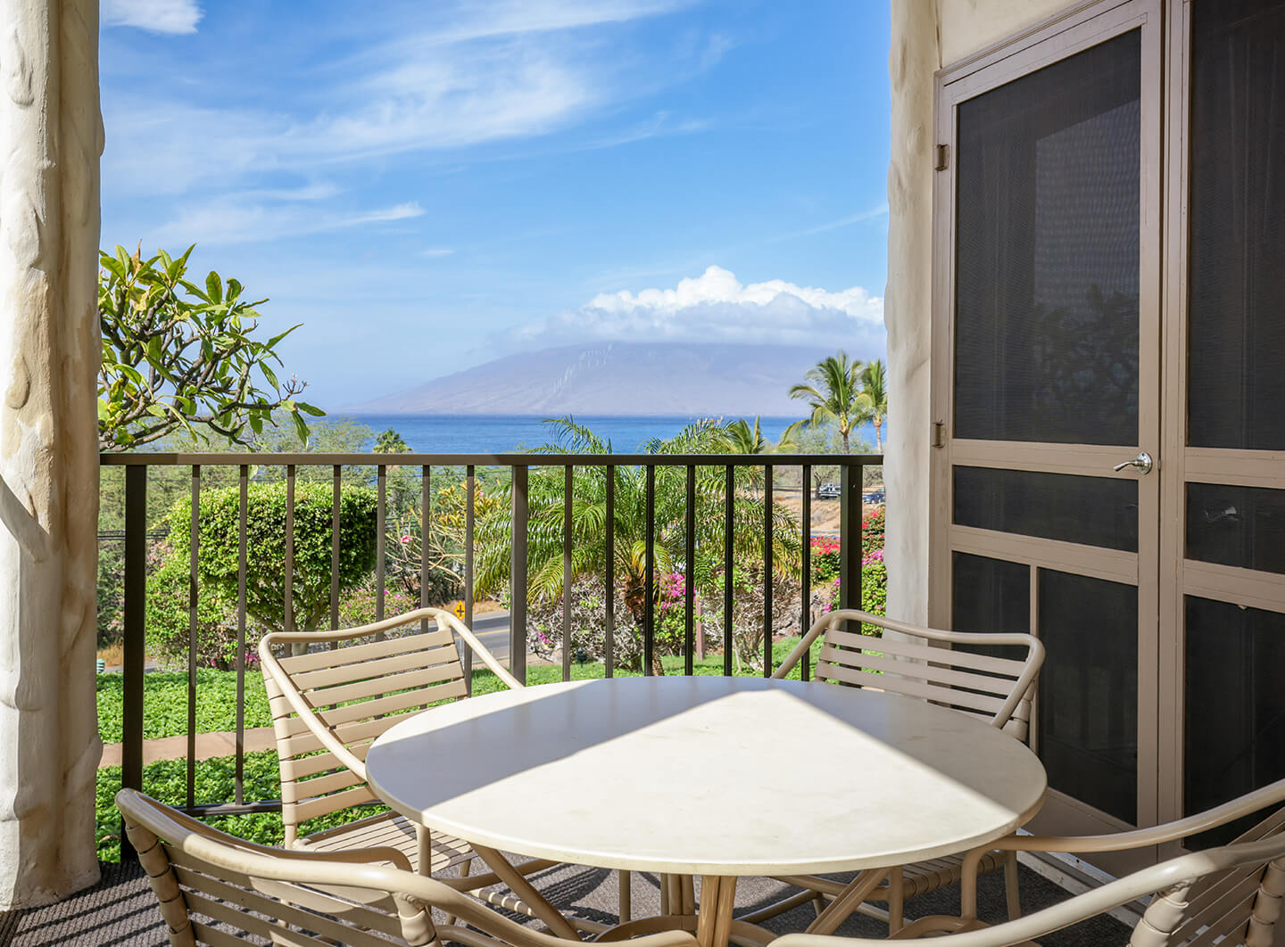 Ocean view from balcony with table and chairs.