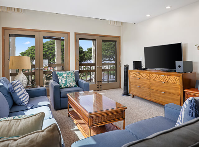 Living room with couch, coffee table, lamps, TV, balcony