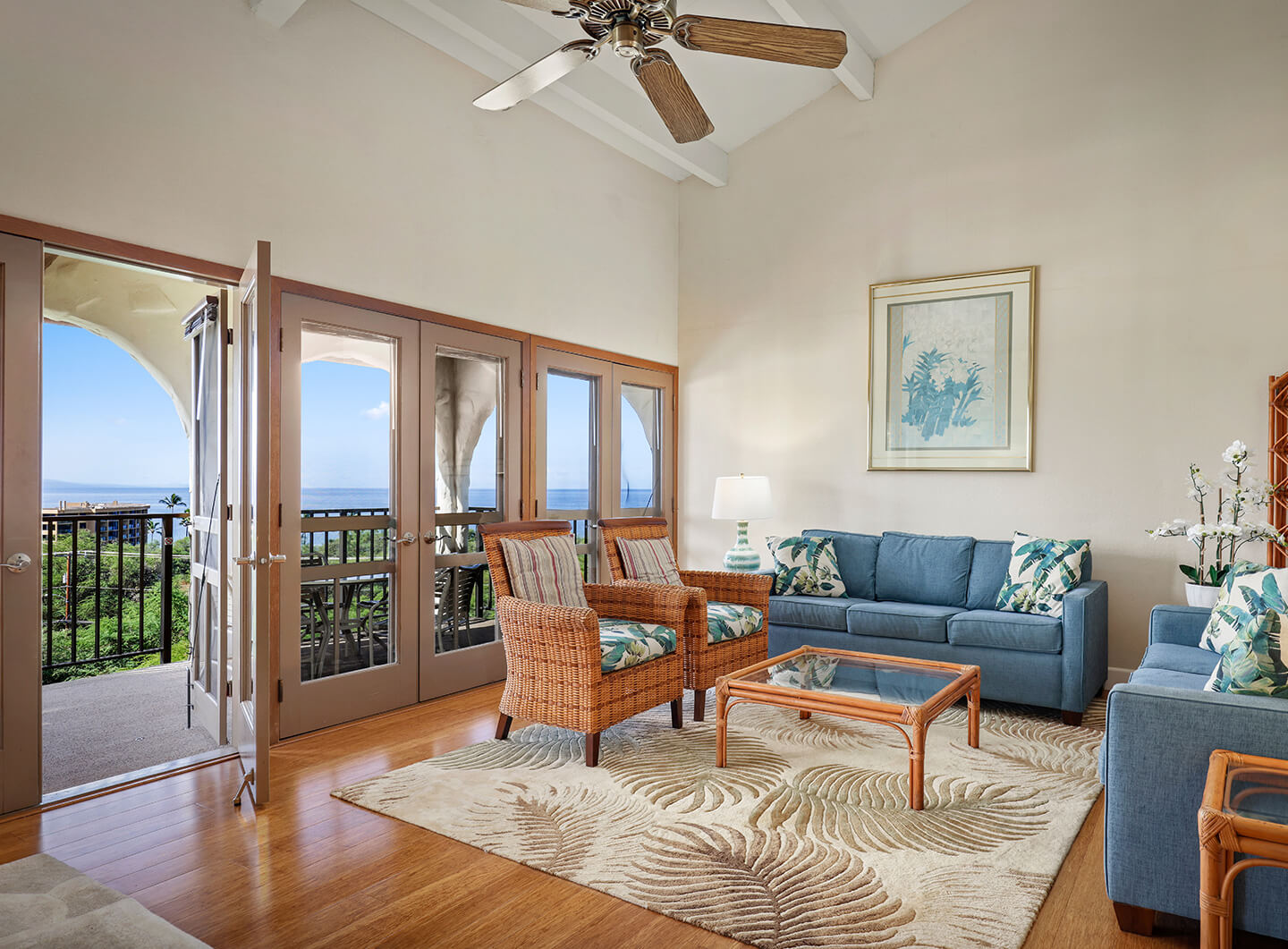 Living area with couch, coffee table, TV, and balcony with ocean views.