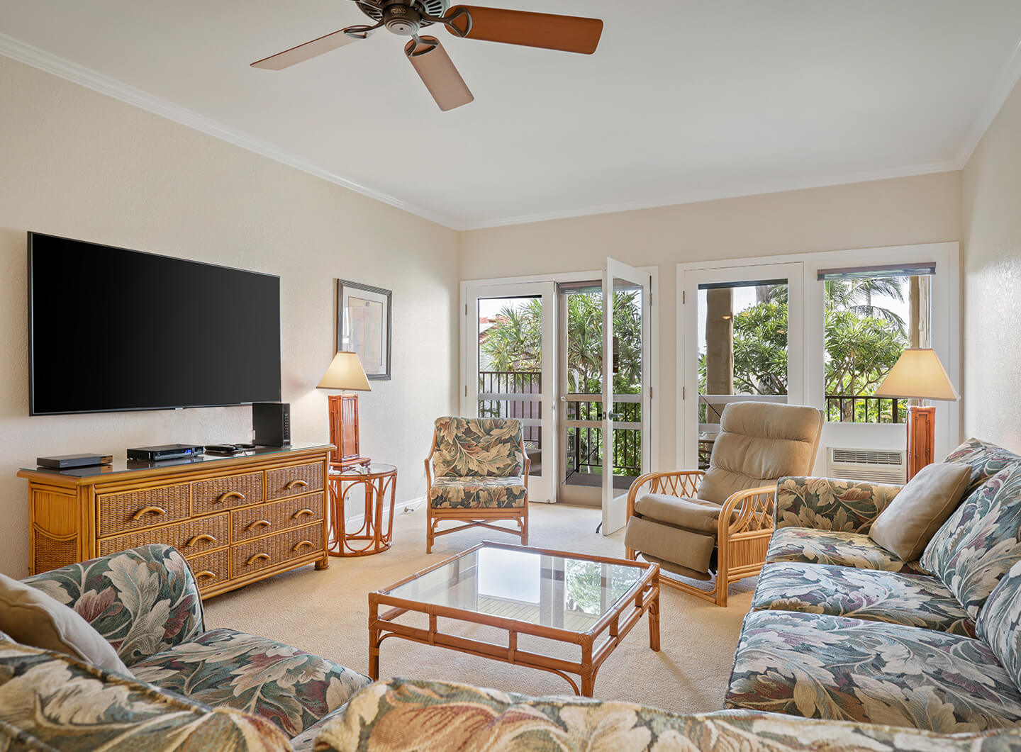 Living area with a couch, coffee table, TV, and balcony.