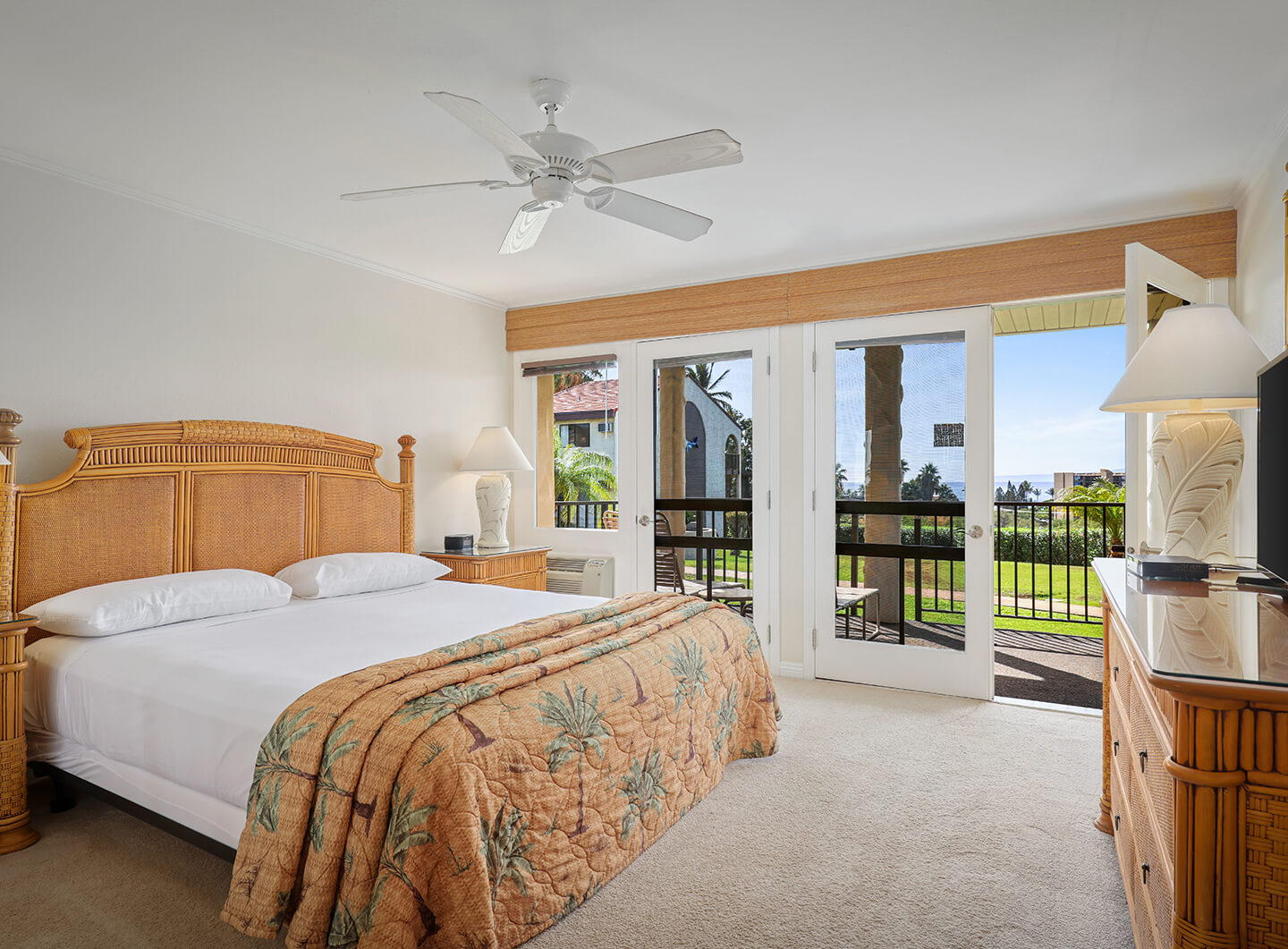Room with a bed, dresser, TV, and balcony.