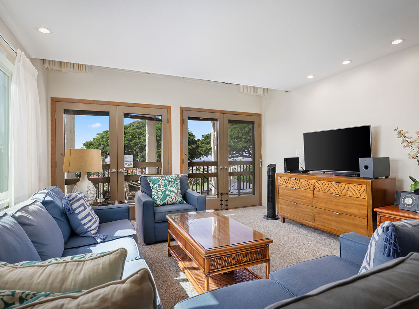 Living area with a couch, coffee table, TV, and balcony.