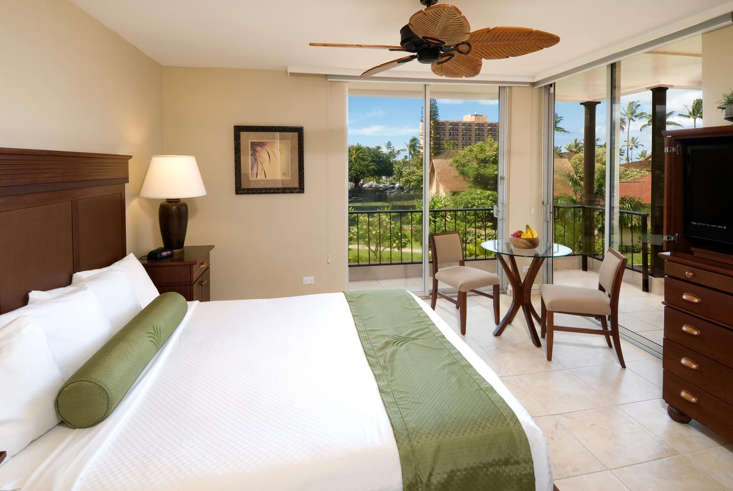 Room with a bed, nightstand, lamps, TV, dining area, and balcony.