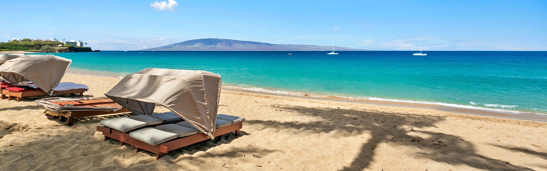 Sand beach with cabanas and views of island in distance