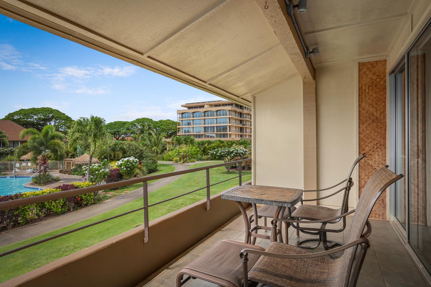 Balcony with lounge chairs and view of resort pool and lawns.