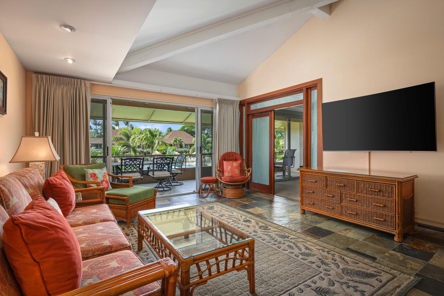 Living area with a couch, coffee table, TV, and balcony.