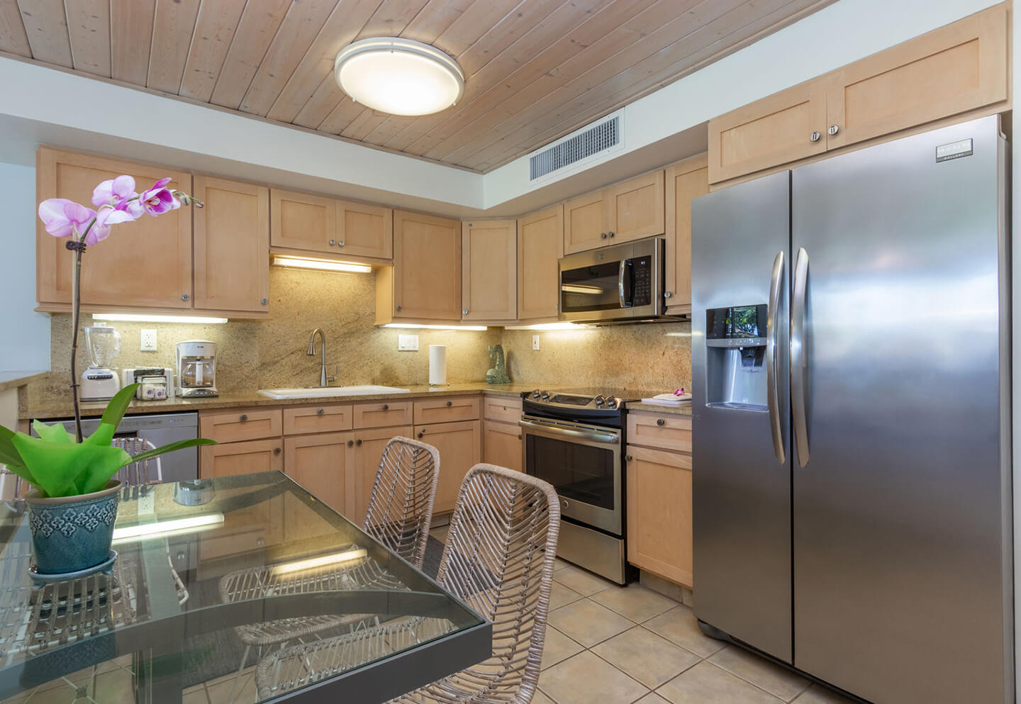 Kitchen with refrigerator, stove, microwave, sink, and dining table.
