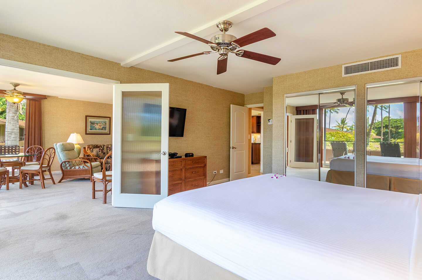 Room with a bed, mirrored closets, and large doorway to living area.