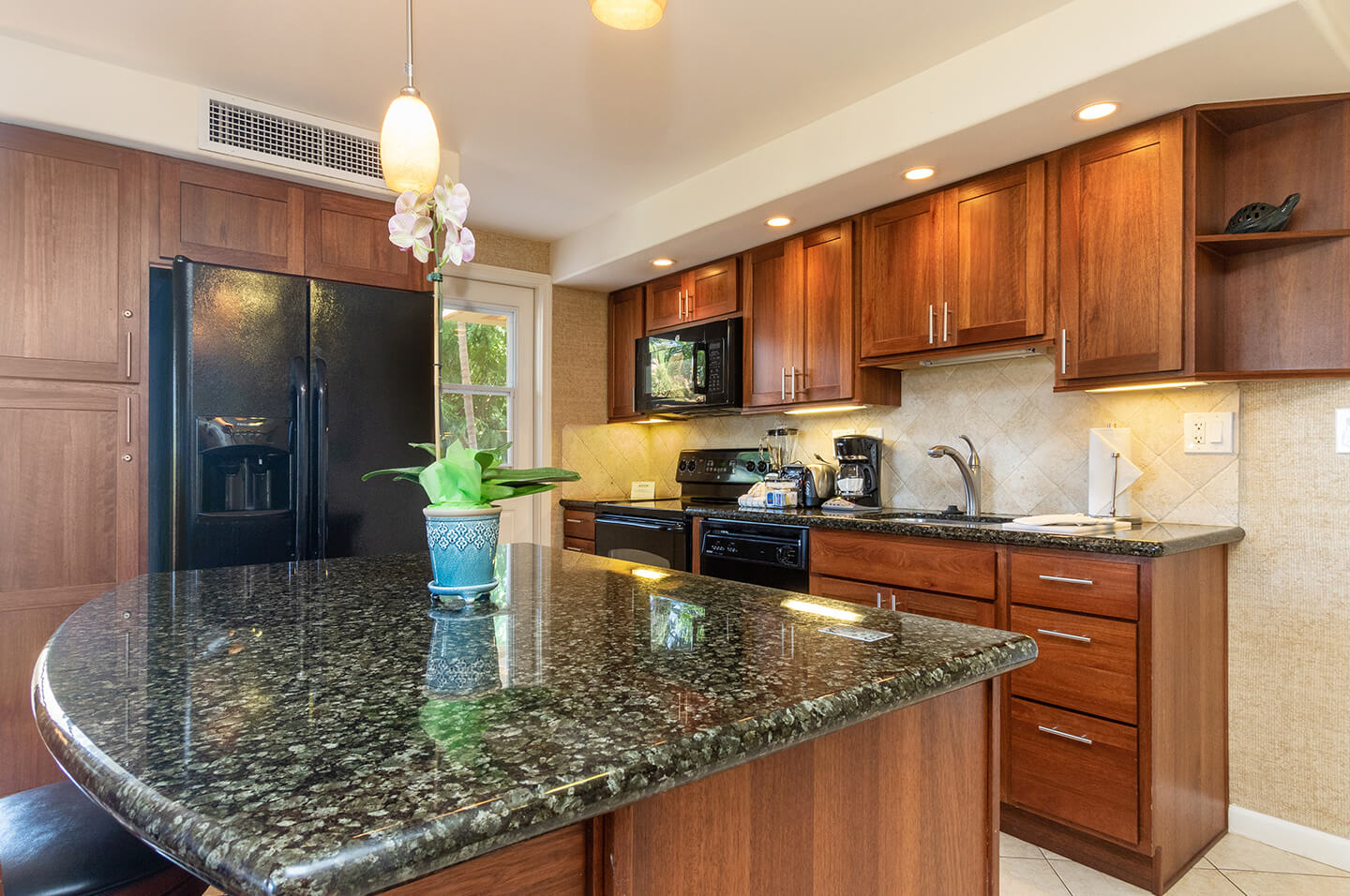 Kitchen with refrigerator, stove, microwave, sink, counters, and cabinets.