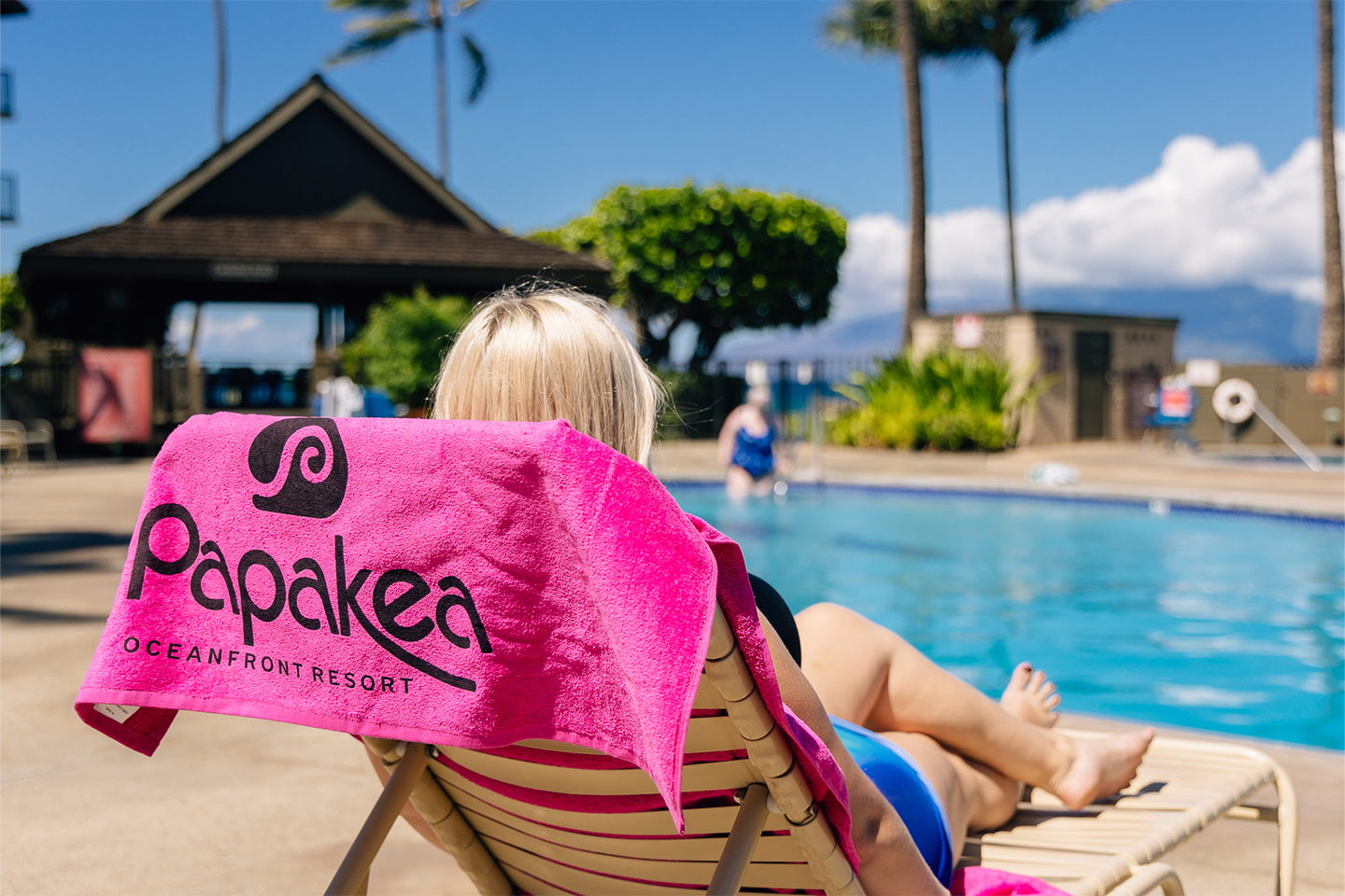 Woman relaxing on lounger at pool.