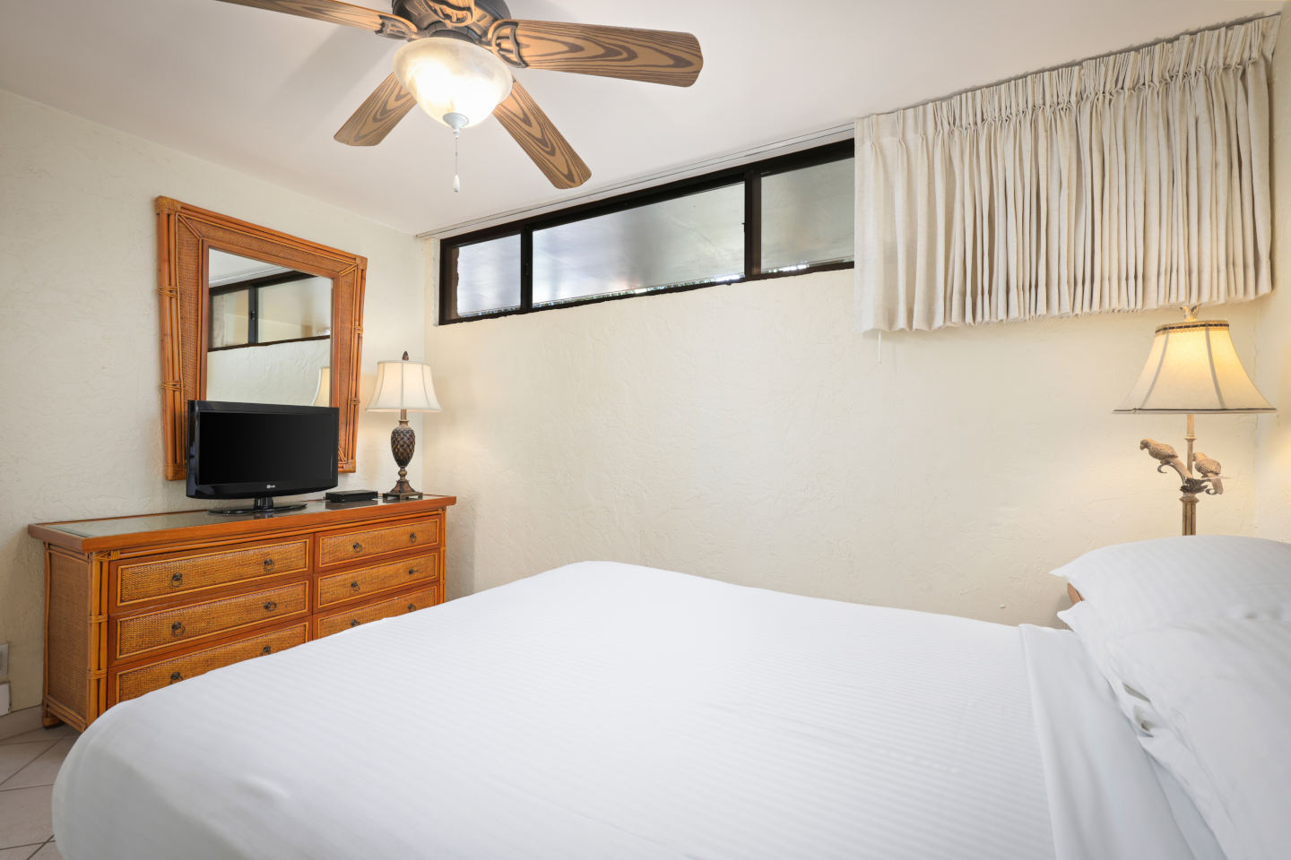 Room with a dresser, bed, lamps, TV.