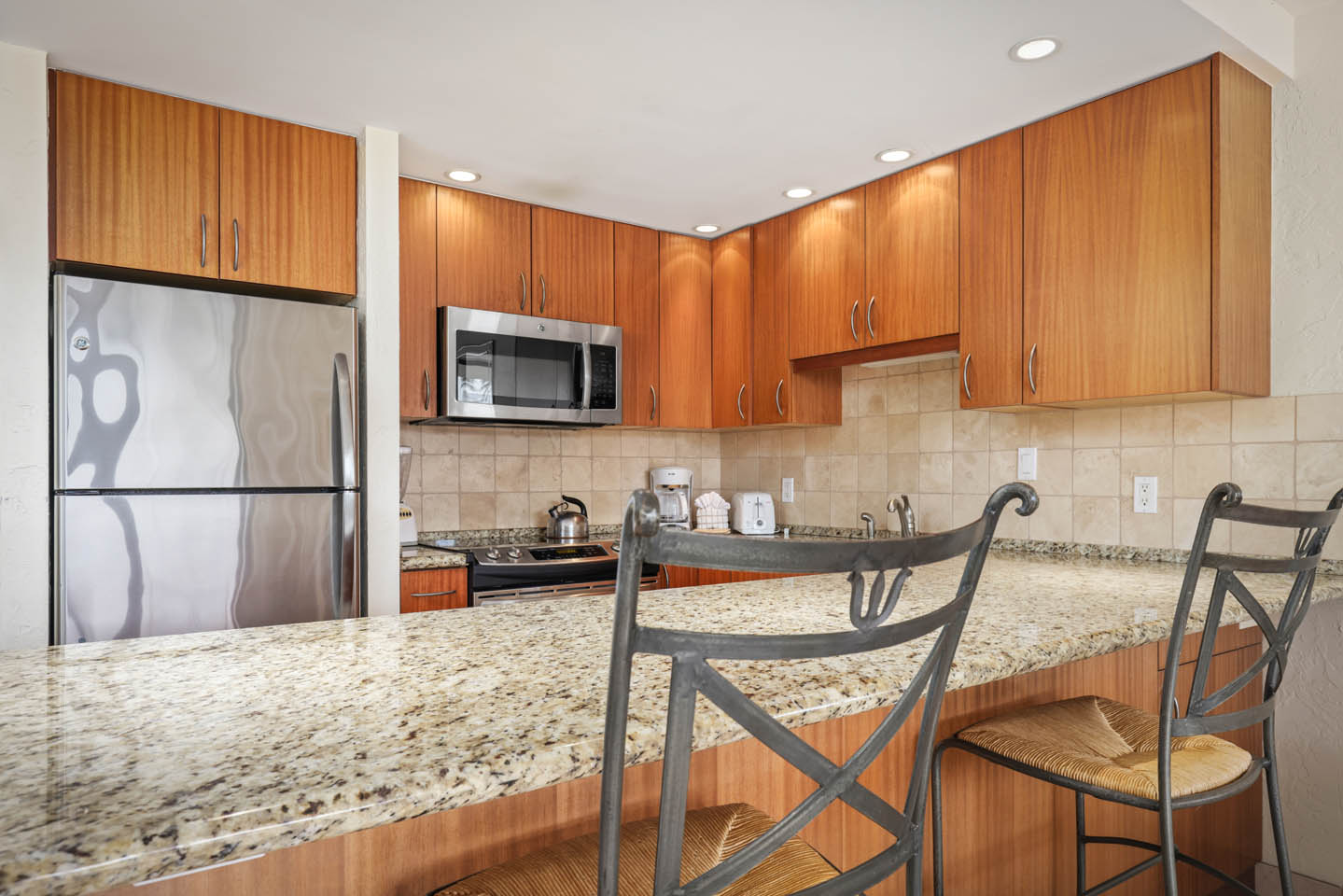 Kitchen with a refrigerator, microwave, countertop seating.