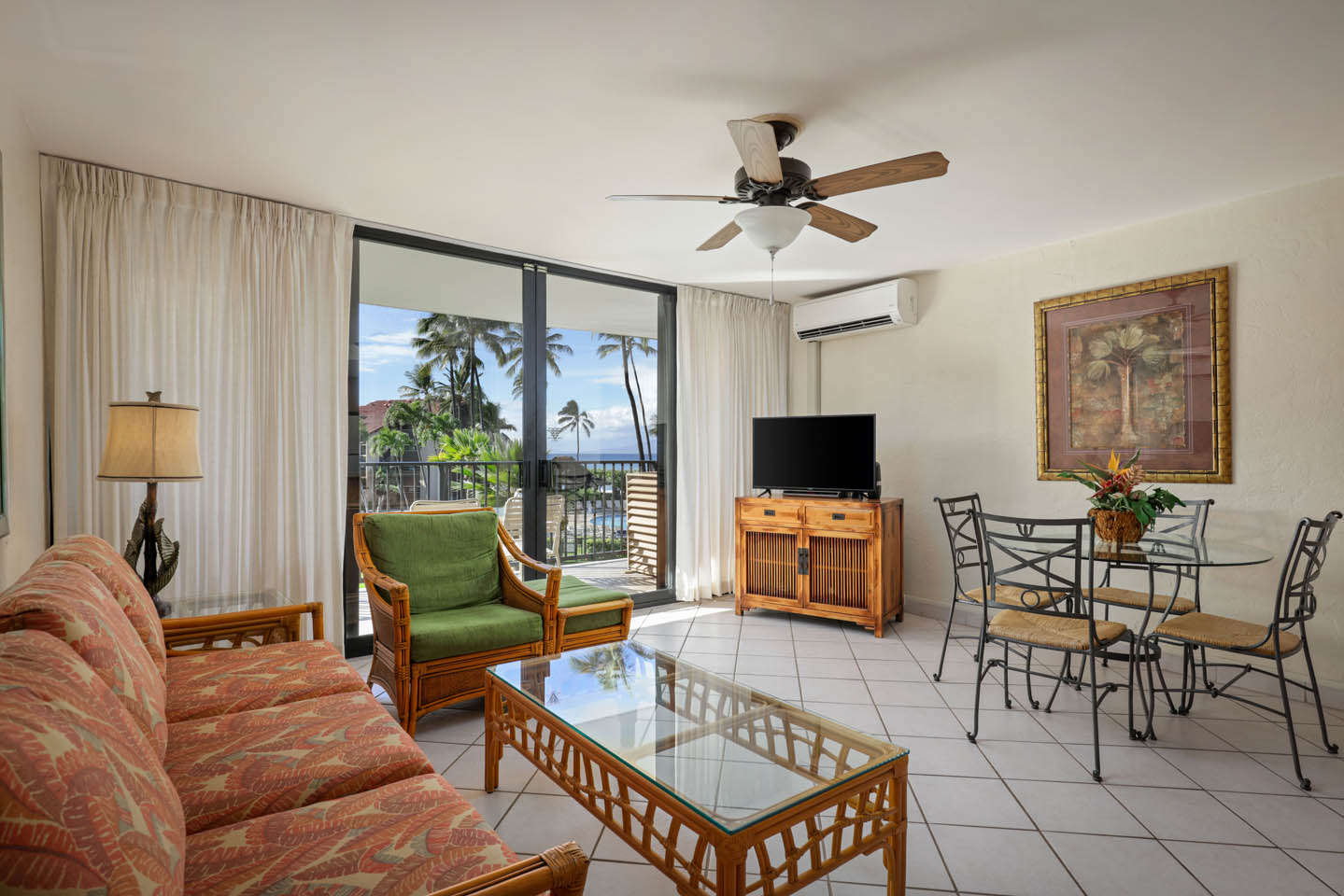 Living area with couch, coffee table, TV, balcony.