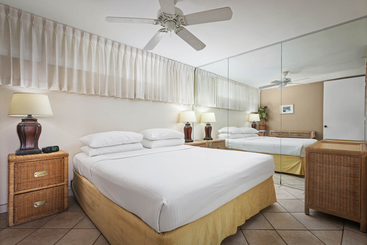 Room with bed, lamps, nightstand, mirrored wall.