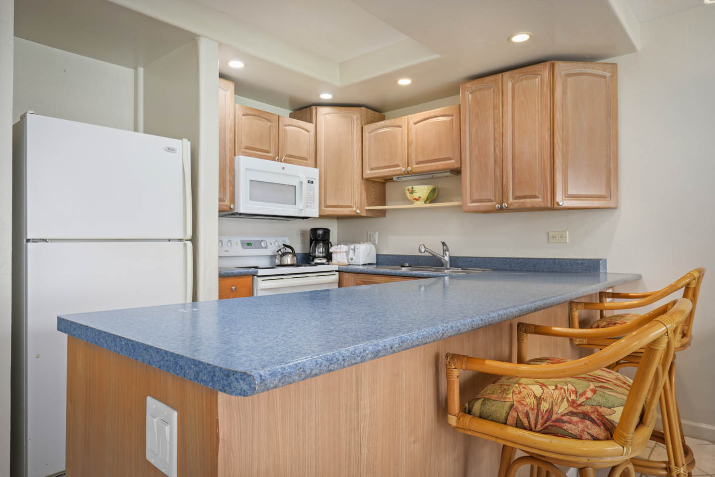 Kitchen with countertop seating, refrigerator, stove, and microwave