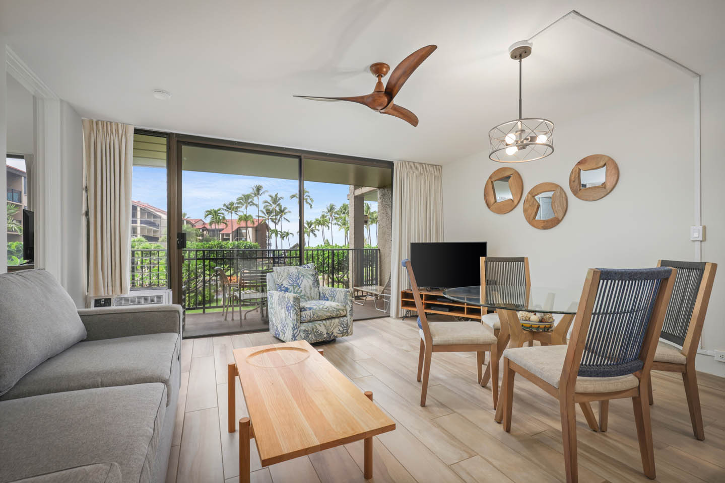 Living area with a couch, seating, coffee table, dining area, TV, and balcony.