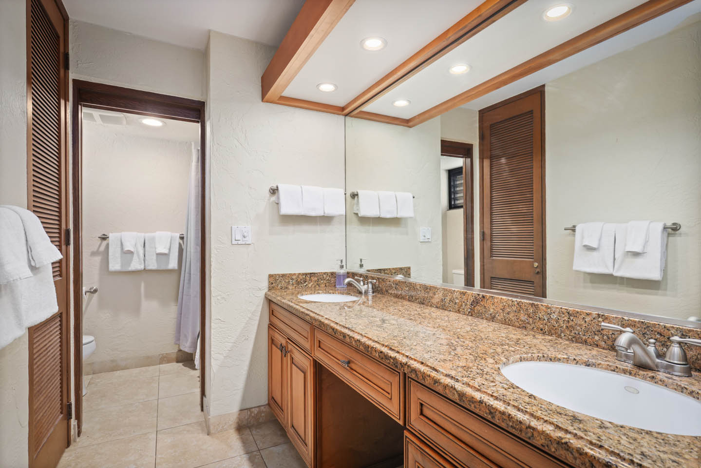 Bathroom with counter, 2 sinks, toilet, shower.
