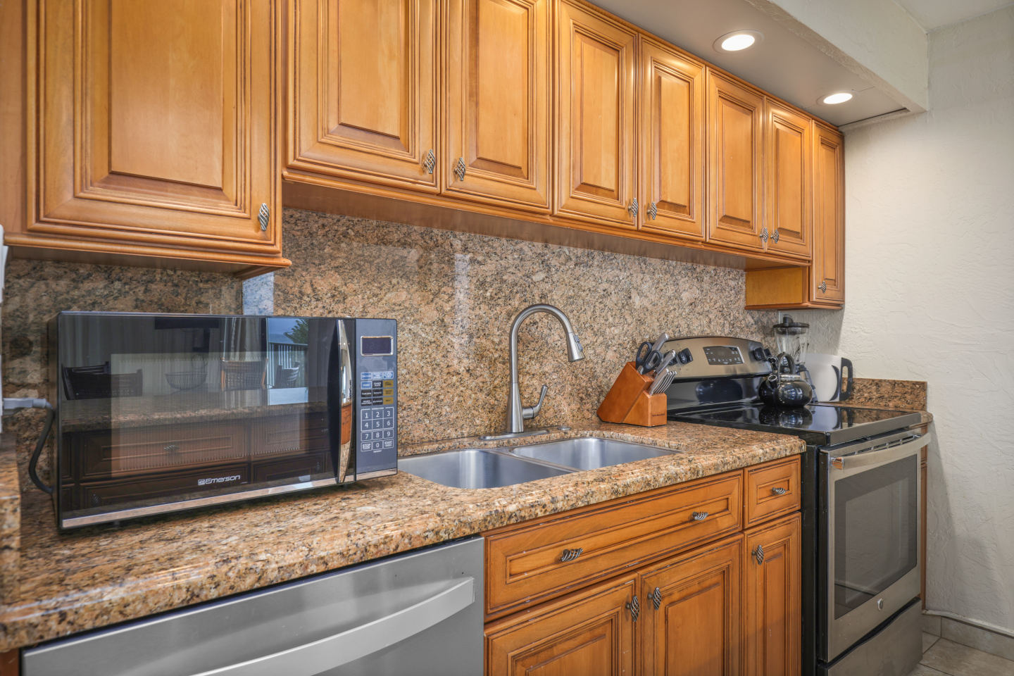 Kitchen with a refrigerator, microwave, sink, and stove. 