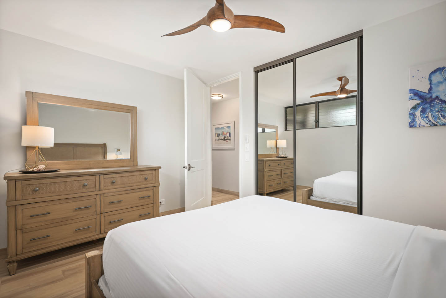 Loft room with bed, lamps, dresser, mirrored closet.