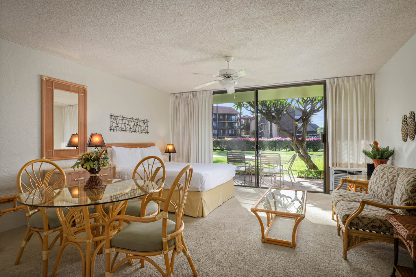 Room with dining table, chairs, seating area, coffee table, bed, and balcony.