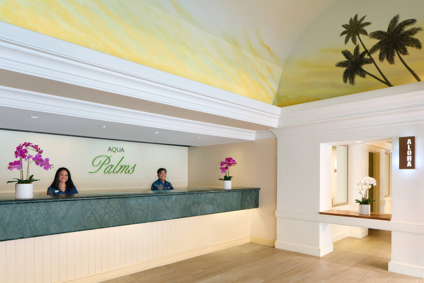 Aqua Palms signage behind hotel front desk and associates.