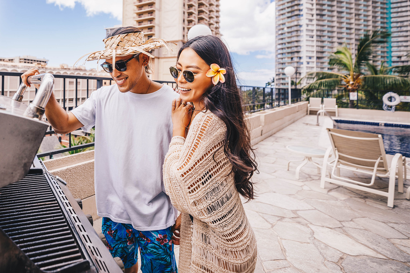 Couple looking at bbq grill on pool deck.