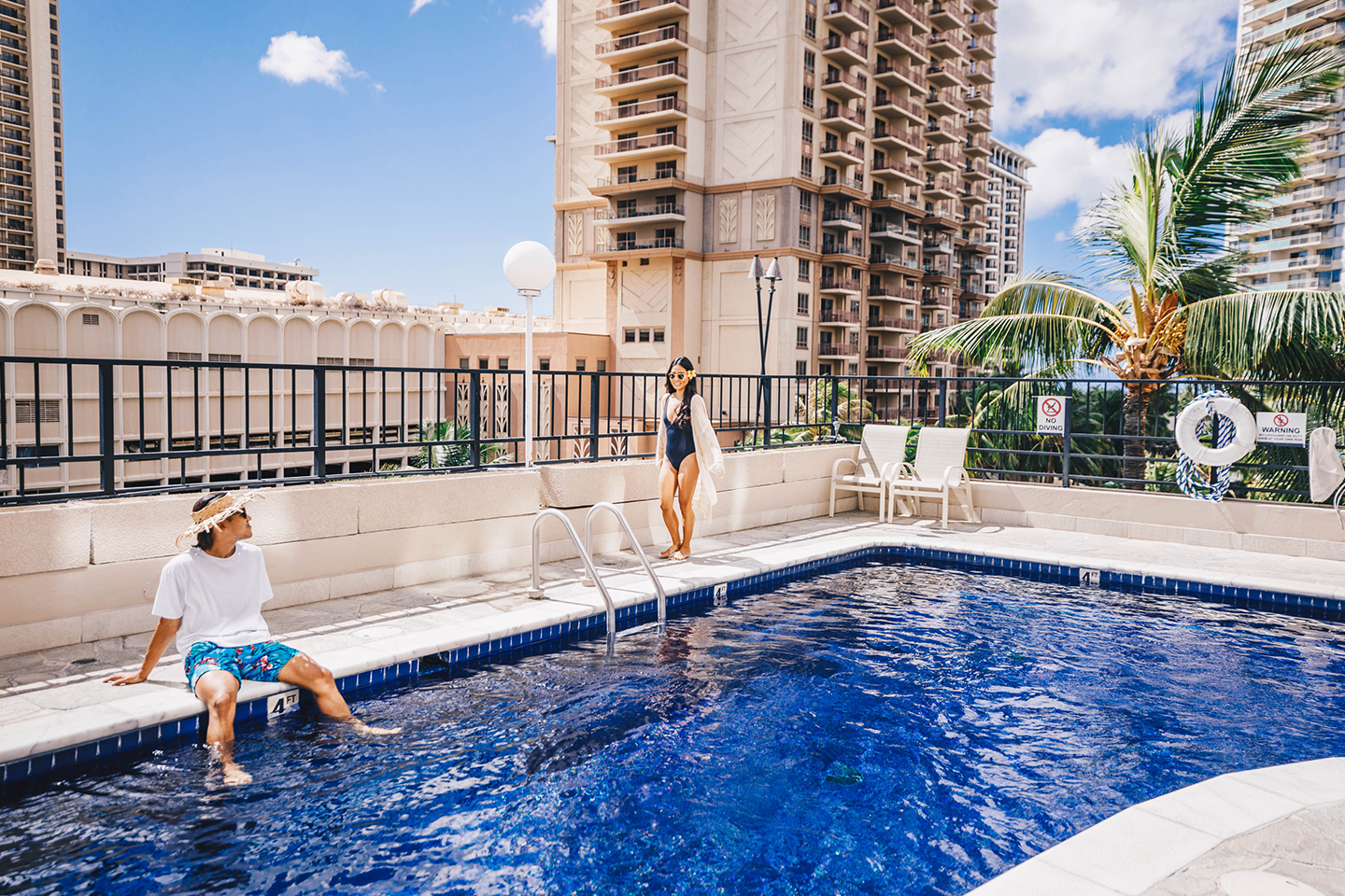 Man and woman hanging out on pool deck.