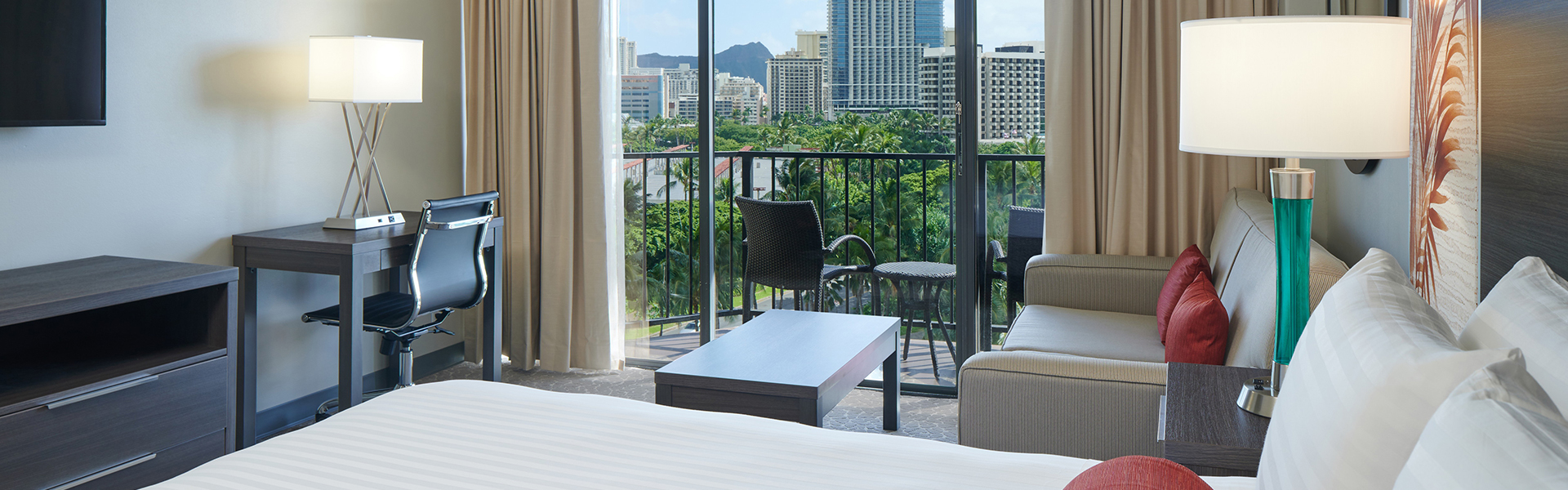 Room with bed, desk, couch, TV, coffee table, and balcony