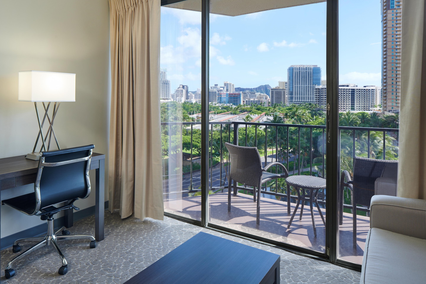 Room with desk, chair, couch, coffee table, balcony.