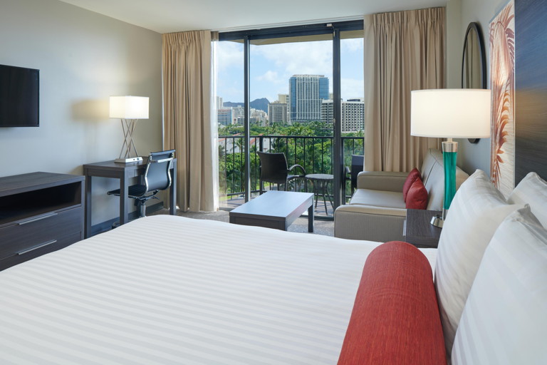Room with bed, couch, coffee table, lamps, balcony