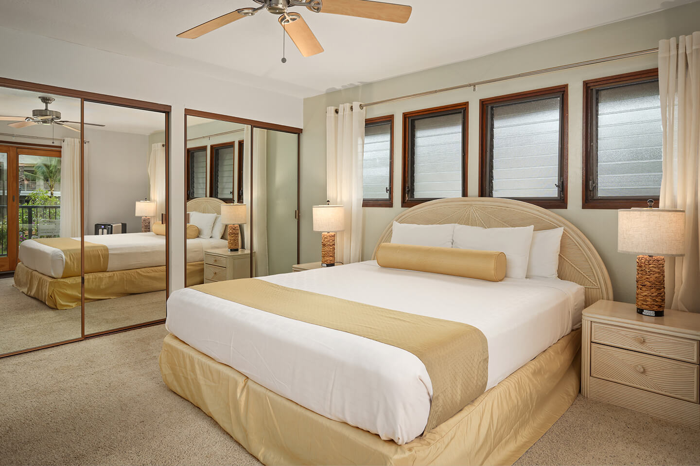 Room with bed, night stand, lamps, large mirriored closets.