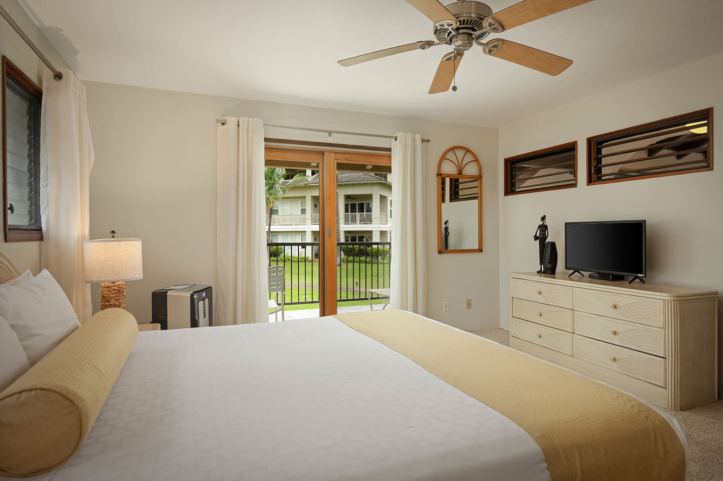 Room with bed, TV, dresser, lamp, patio.