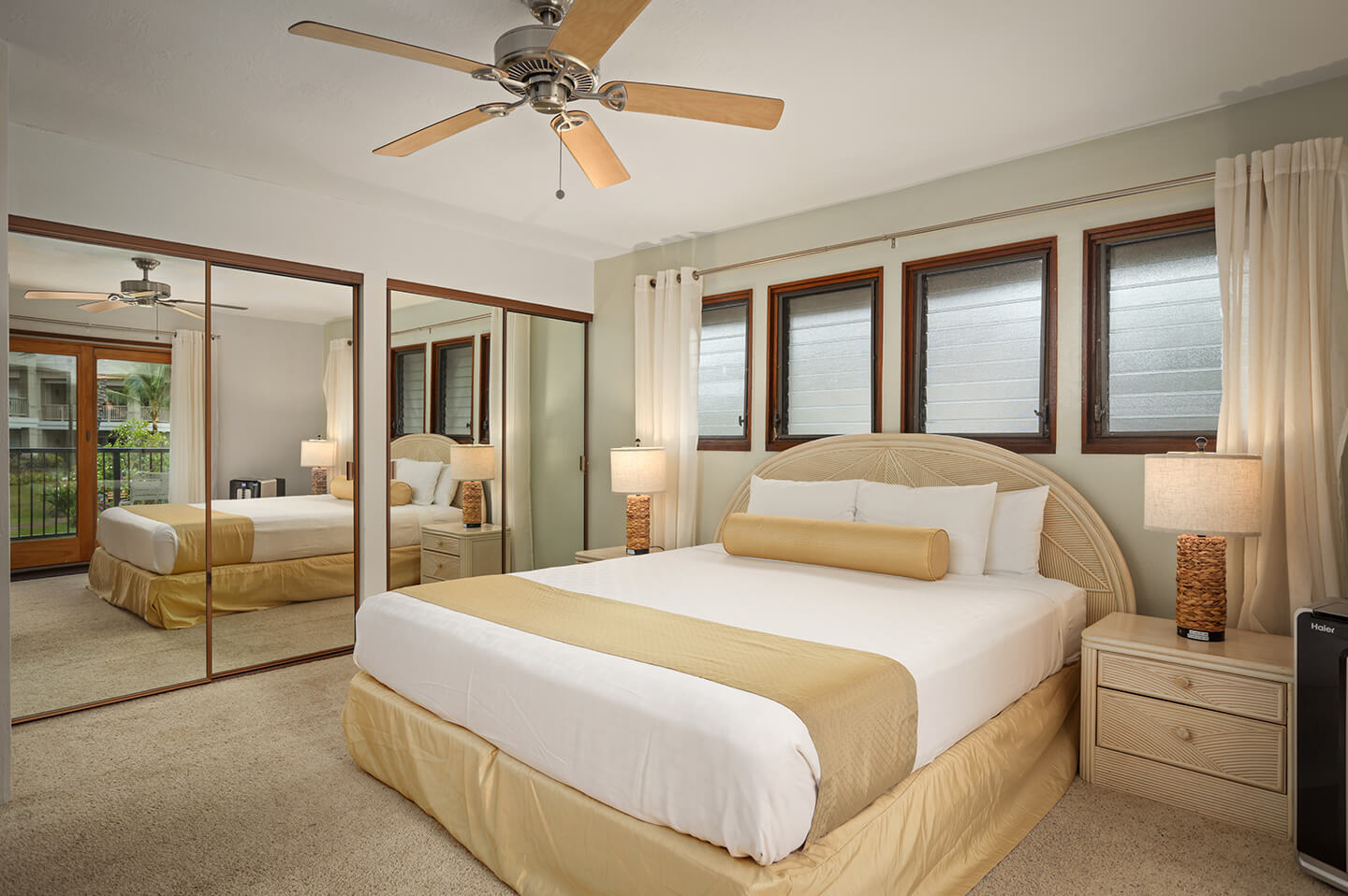 Room with bed, night stand, lamps, large mirriored closets.