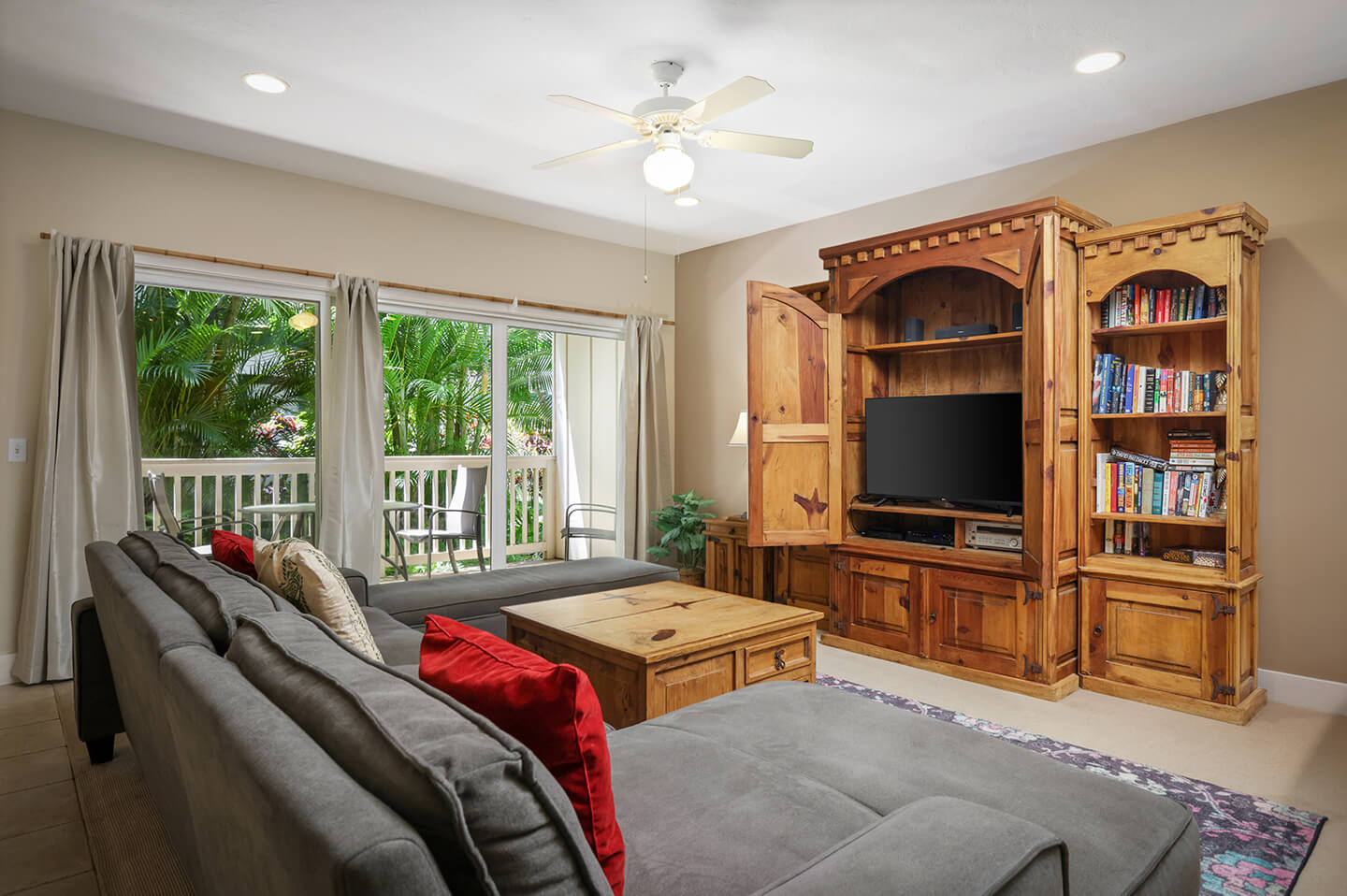 Living area with a couch, coffee table, TV, bookshelf, and balcony.