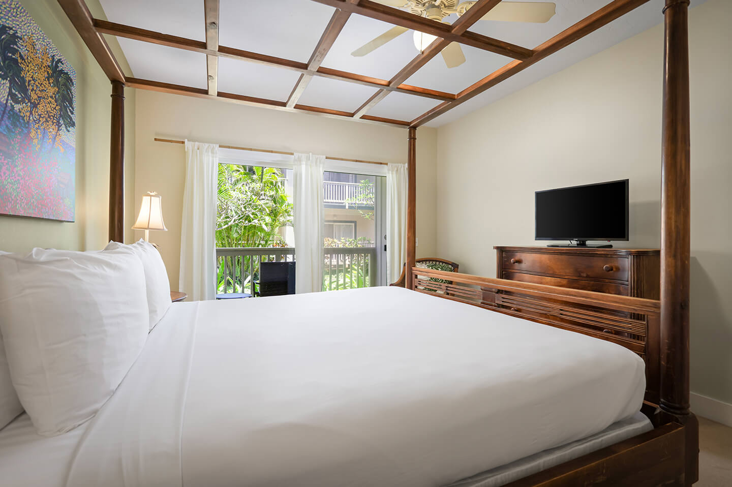 Room with king bed, dresser, TV, balcony.