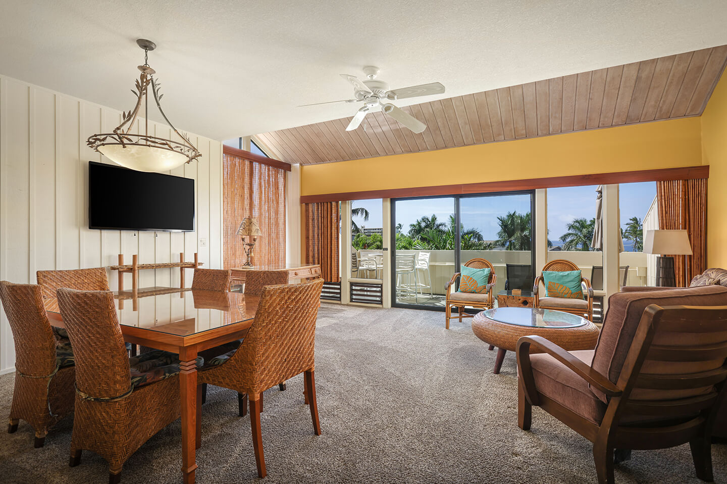 Living area with a couch, coffee table, TV, dining area, and balcony.