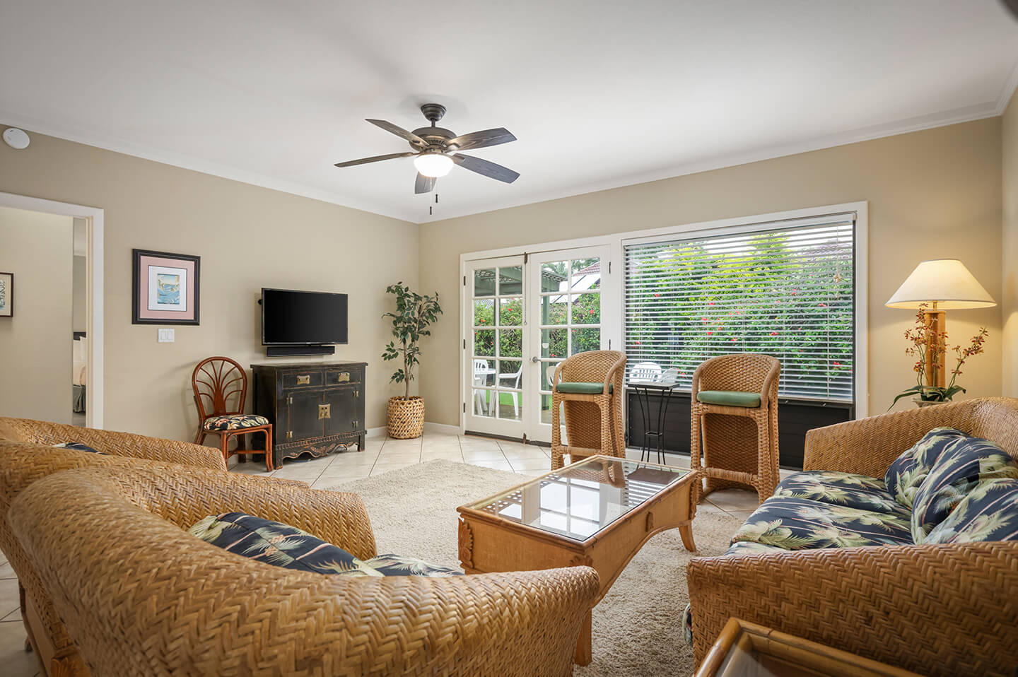 Living area with couch, seating, table, TV, lamps, patio.