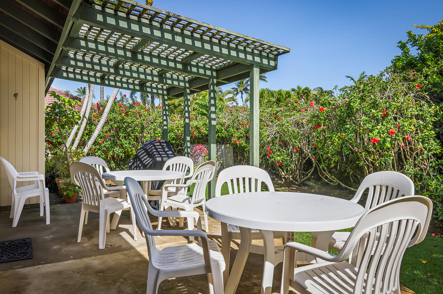 Patio with 2 tables, chairs, overhead covering.
