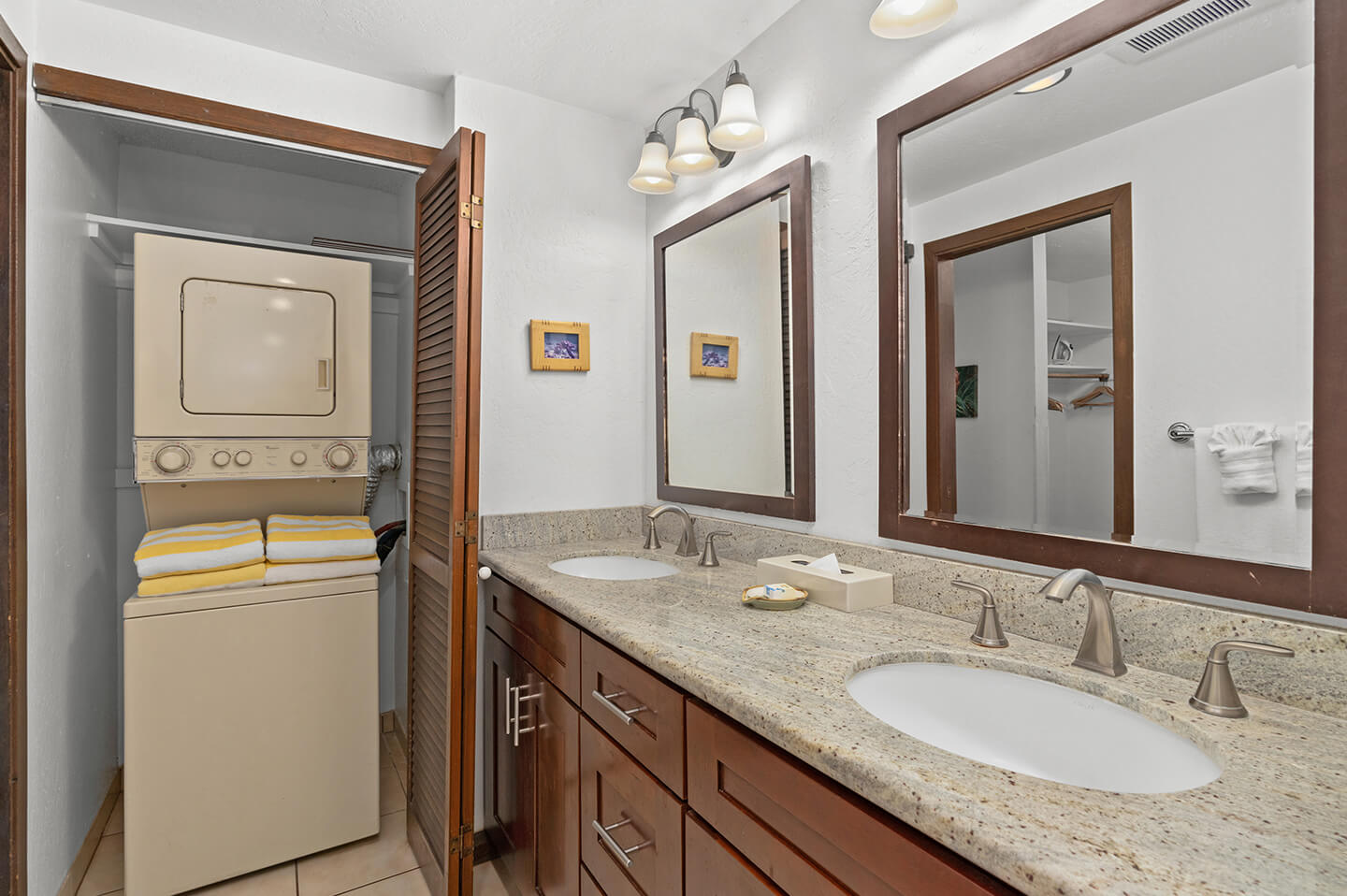 Bathroom counter top, dual sinks, mirror, washer/dryer unit in closet.