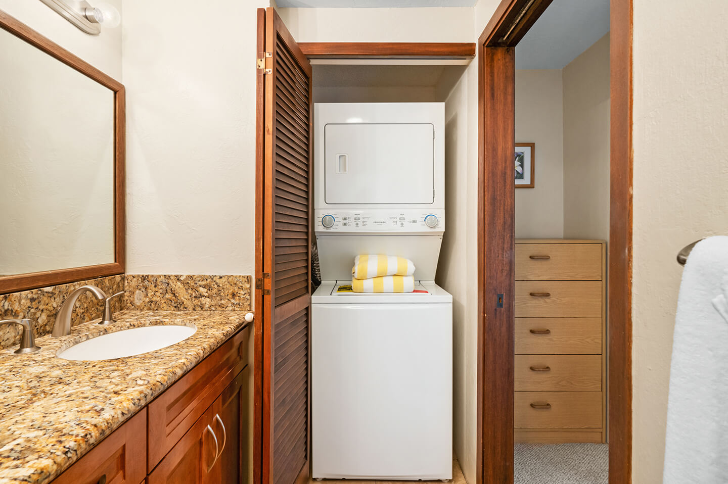 Bathroom counter top, sink, shower, and washer/dryer unit in closet.